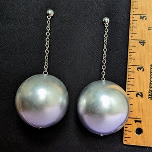 a pair of ball dangle earrings next to a ruler