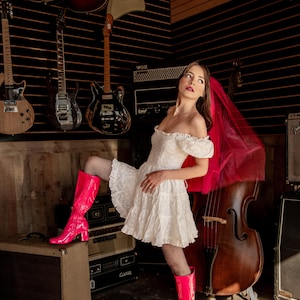 a bride wearing a pink veil and boots