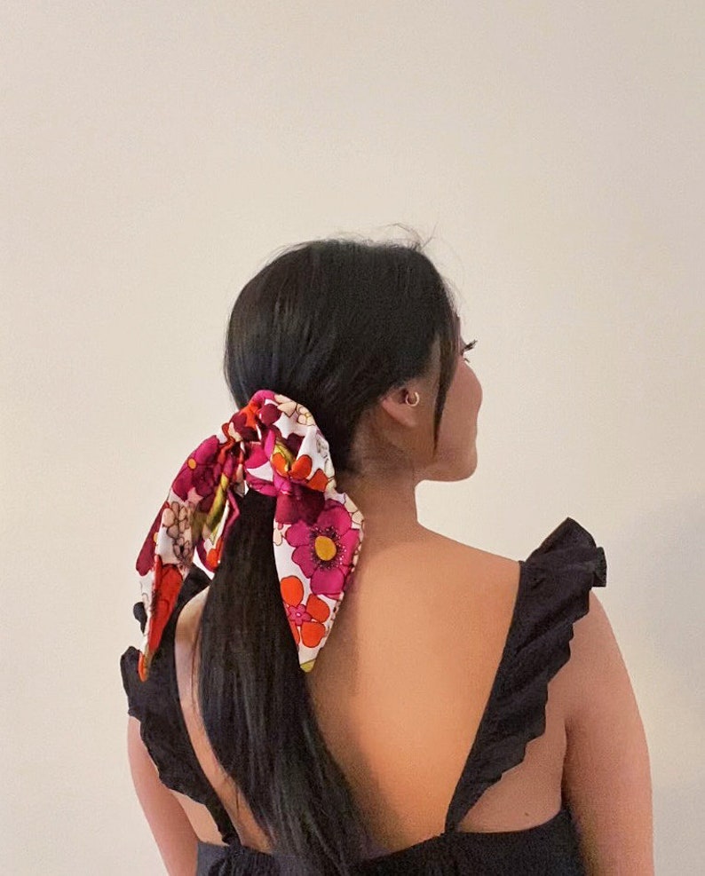 a woman with long black hair wearing a floral bow