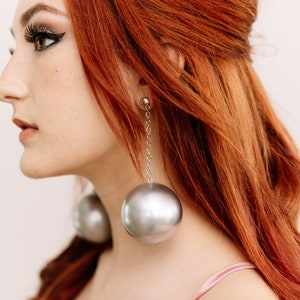 a woman with red hair wearing large earrings