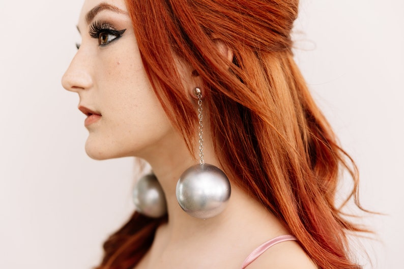 a woman with red hair wearing large earrings