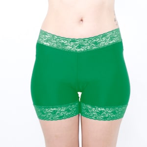 May include: Green spandex shorts with a lace trim. The shorts are a bright, vibrant green and have a delicate lace trim around the waistband and the leg openings.