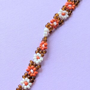 A close-up shot angled diagonally across the length of the seed bead flower necklace.