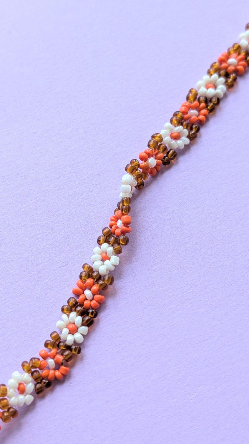 A close-up shot angled diagonally across the length of the seed bead flower necklace.