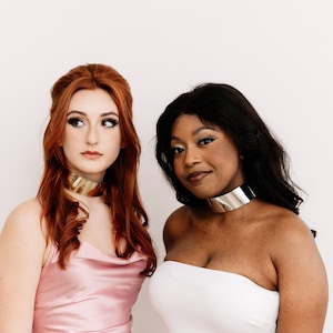 a couple of women wearing metallic choker necklaces
