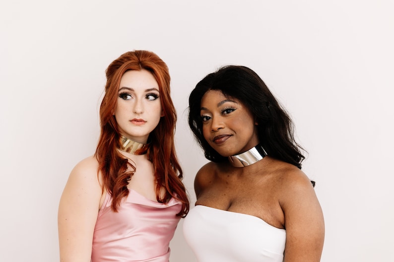 a couple of women wearing metallic choker necklaces