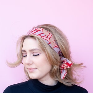 a woman with blonde hair wearing a red and pink head scarf