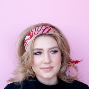 a woman with blonde hair wearing a red and pink head scarf