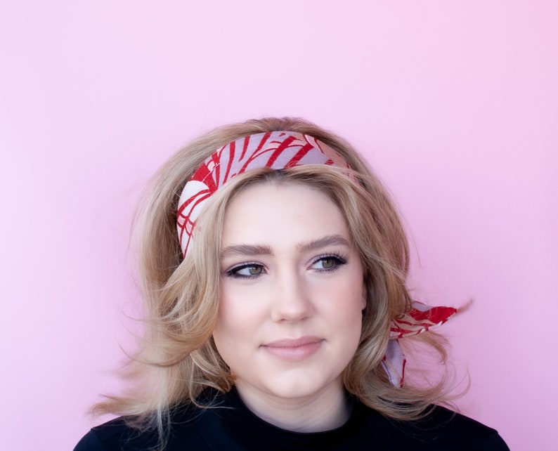 a woman with blonde hair wearing a red and pink head scarf