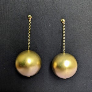 a pair of gold colored earrings hanging from a gold chain
