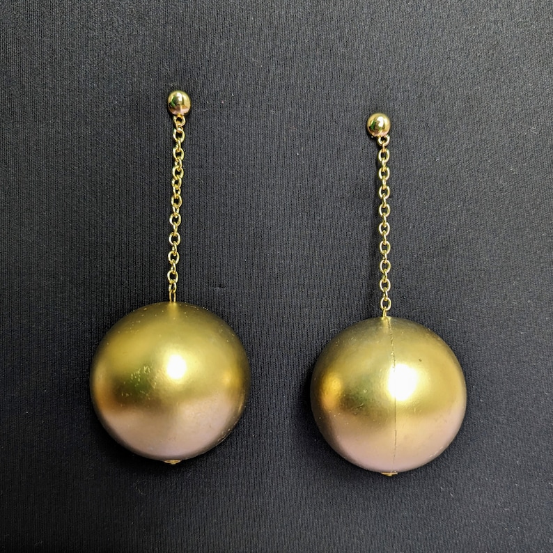 a pair of gold colored earrings hanging from a gold chain