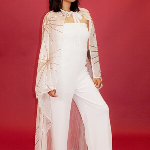 a woman in a white jumpsuit with sheer sleeves