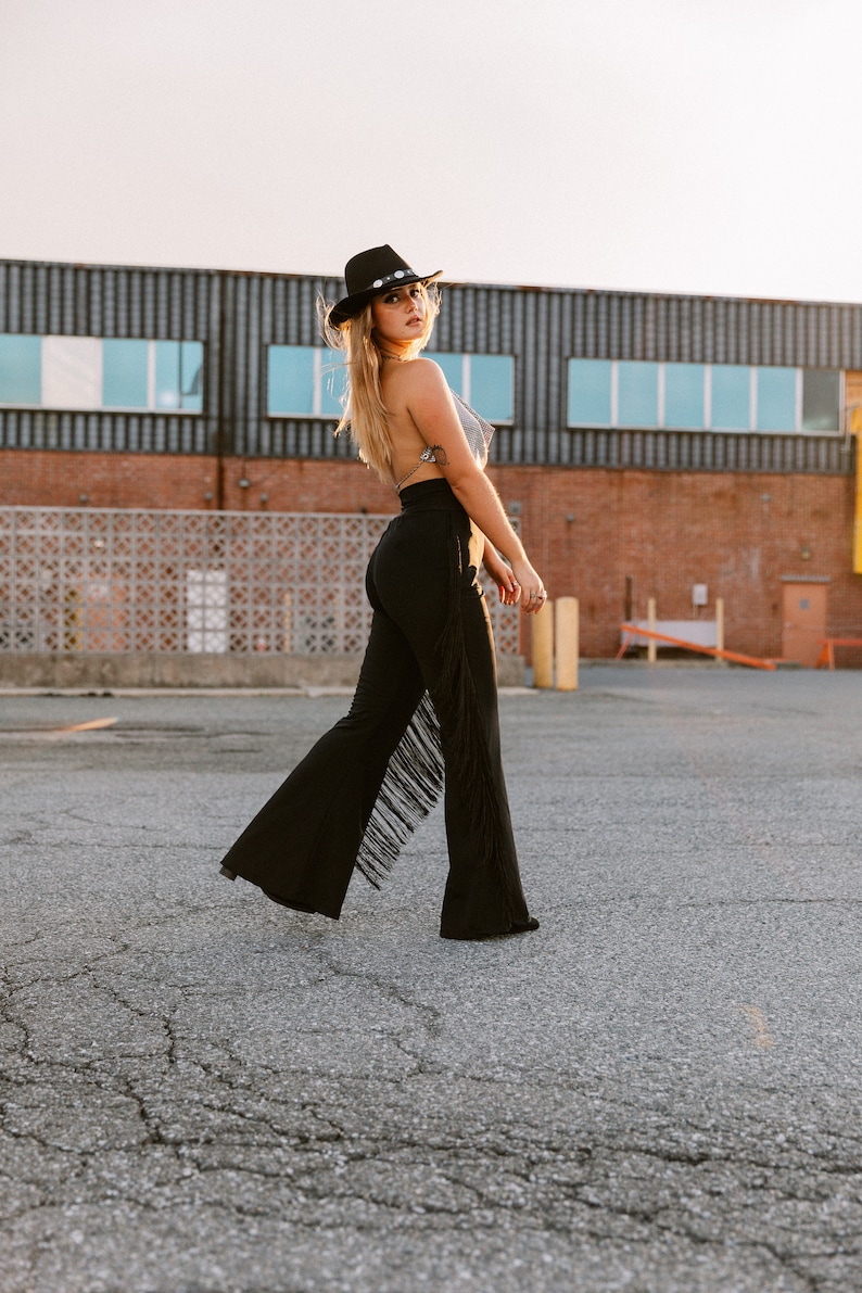 a woman walking across a parking lot wearing a black hat