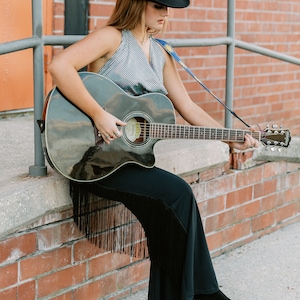 a woman in a cowboy hat playing a guitar