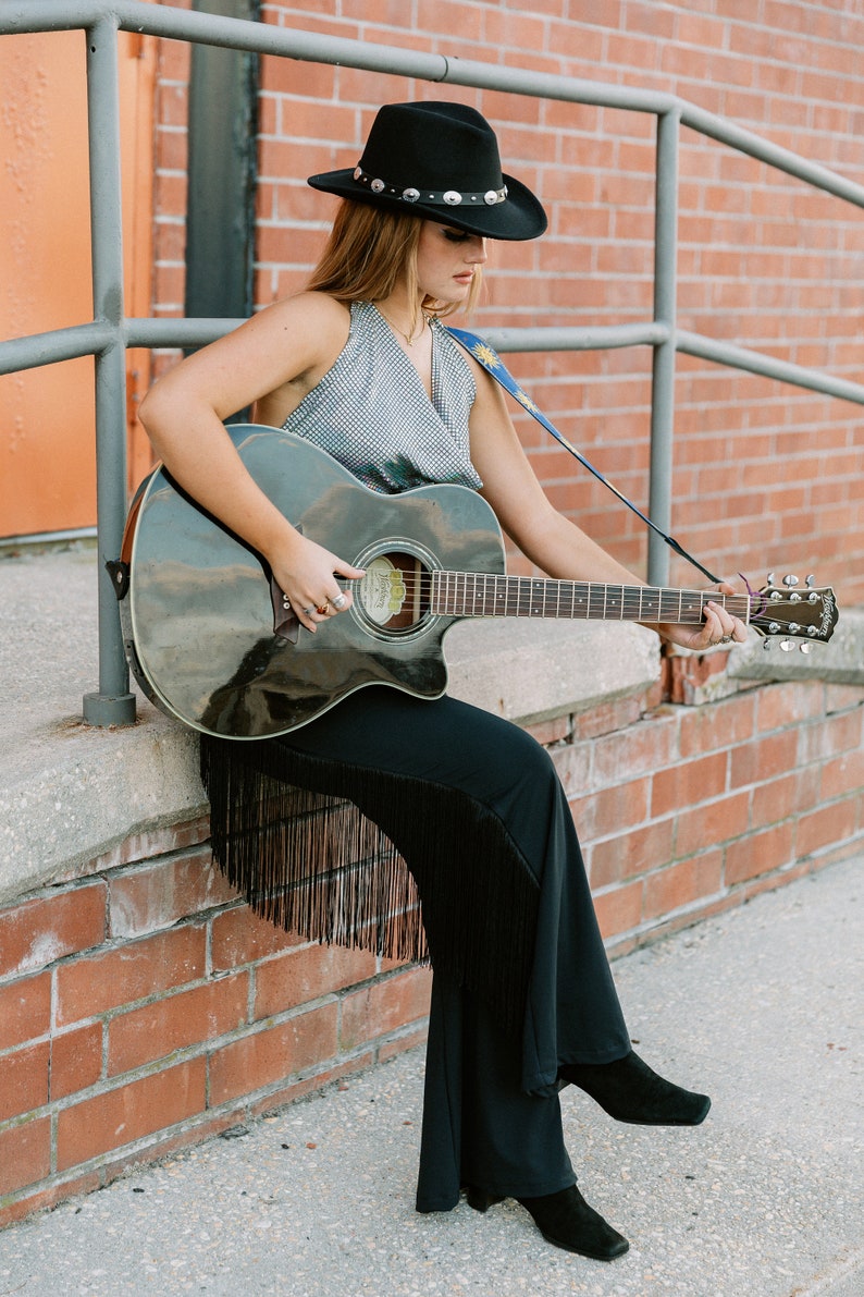 a woman in a cowboy hat playing a guitar