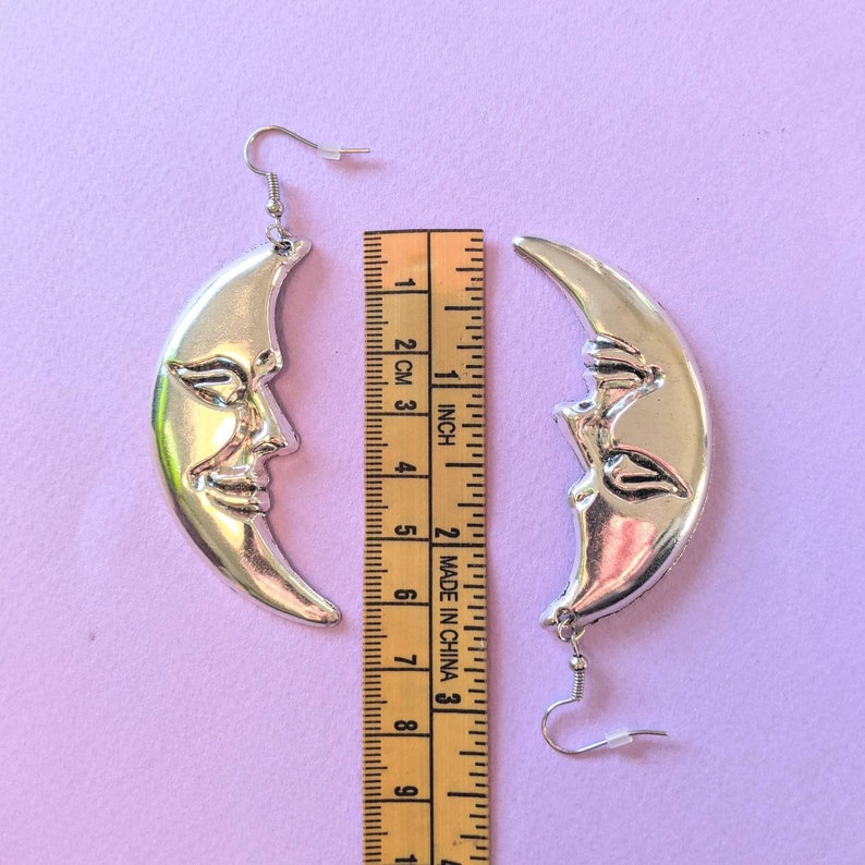 moon shaped earrings next to measuring tape