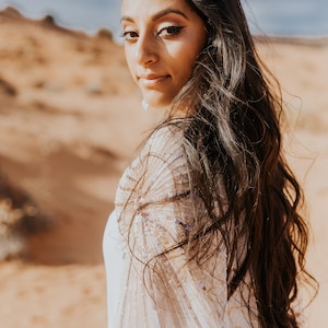 a woman with long hair standing in the desert