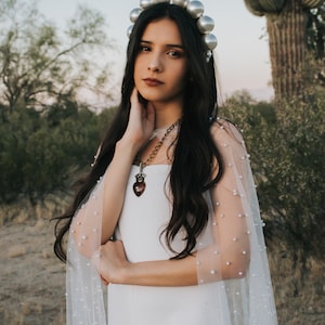 a woman in a white dress and bridal cape