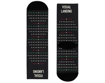 May include: A pair of black crew socks featuring a repeating pattern of small white, red, and green dots arranged in horizontal rows. The text "VISUAL LANDING" is printed in white capital letters at the top and bottom of the sock design.