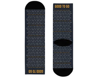 Könnte beinhalten: Ein Paar dunkelmarineblaue Socken mit einem sich wiederholenden Muster aus weißen und gelben alphanumerischen Flugdatencodes. Der Text GOOD TO GO ist oben und unten auf den Socken in Gelb aufgedruckt. Ferse und Spitze sind schwarz.