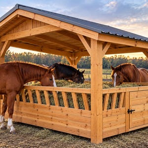 Puede incluir: Un comedero de madera para caballos con techo, que cuenta con un henil de listones y una puerta de acceso lateral. Tres caballos comen heno de la estructura, construida con vigas y tablones de madera clara y un techo de metal oscuro.