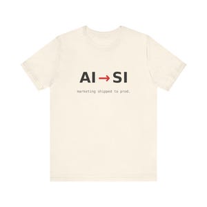 May include: A cream-colored short-sleeve t-shirt featuring the black text AI, a red arrow, and the black text SI. Below this, the text marketing shipped to prod. is printed in a smaller, typewriter-style black font centered on the chest.