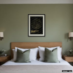Puede incluir: Una lámina de arte mural rectangular enmarcada con fondo oscuro, una imagen lunar tenue y el texto THE MOON IN BINARY en amarillo. La lámina se presenta en un marco negro centrado en una pared verde salvia sobre un cabecero de madera.