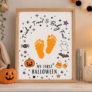 May include: A framed rectangular print featuring orange baby footprints in the center, surrounded by Halloween icons including a pumpkin, ghost, bat, spider, and candy corn, with the text Trick or Treat & Baby Feet My First Halloween.