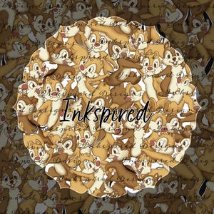 May include: A repeating pattern of cartoon chipmunks in various poses, featuring brown and tan fur, large eyes, and small noses. The word Inkspired is written in a black cursive font across the center of the circular design, layered over the characters.