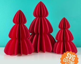 May include: Three red paper Christmas trees of varying sizes. The trees have a layered, rounded design, with a textured appearance. The background is a solid teal color. The trees are on a white surface. The image includes the text "SVG CUTTING FILE".