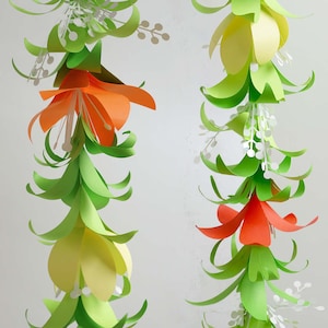Pu&ograve; includere: Una ghirlanda di fiori di carta con foglie verdi e dettagli bianchi. I fiori sono arancioni, gialli e rossi.