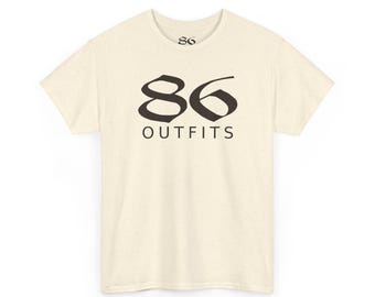 May include: A cream-colored short-sleeve t-shirt with subtle speckles throughout the fabric. The front features the black text 86 OUTFITS in a stylized font, and the inner neckline displays the number 86 in a smaller black font.