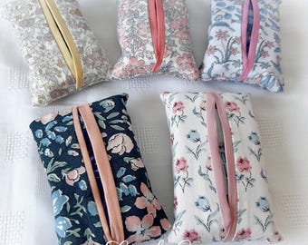 May include: Five floral fabric tissue box covers in various colours. The covers have a rectangular shape with a slit opening and a ribbon accent. The fabrics include patterns with pink, blue, and yellow flowers.