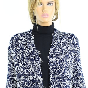 May include: A blue and white open-front cardigan with a fluffy texture. The cardigan has a long, loose fit and is made of a soft, comfortable material.