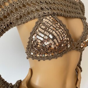 May include: A brown crochet top with long sleeves and a sequined bikini top. The bikini top has a halter neck style and is decorated with gold sequins.