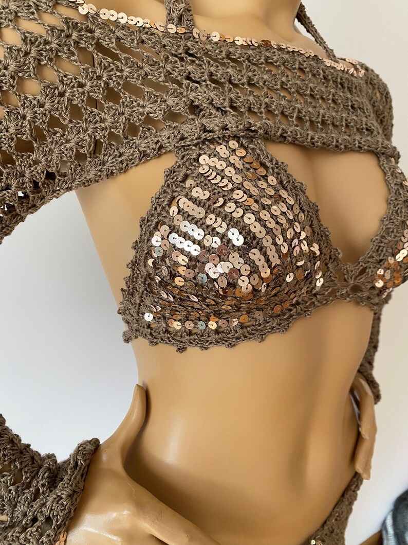 May include: A brown crochet top with long sleeves and a sequined bikini top. The bikini top has a halter neck style and is decorated with gold sequins.