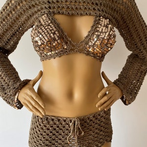 May include: A brown crochet top with long sleeves and a matching brown crochet skirt. The top has a halter neckline and a sequined bodice.