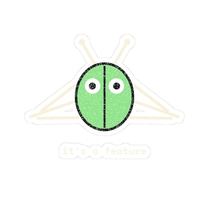 Peut inclure: Un autocollant représentant un personnage ovale vert clair ressemblant à un insecte avec deux yeux noirs et une ligne noire verticale au centre. Derrière l'ovale, quatre bâtons beiges sont disposés comme des pattes. Le texte it's a feature est inscrit.