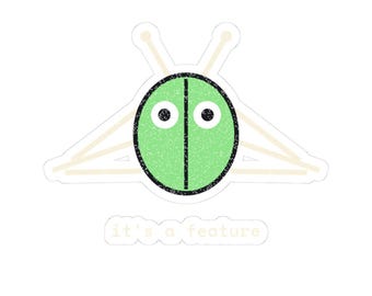 May include: A sticker featuring a light green oval bug-like character with two black eyes and a vertical black line down the center. Behind the oval are four beige sticks arranged like legs. Below the character is the text it's a feature.