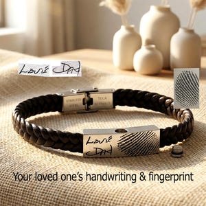 May include: A black braided leather bracelet with a stainless steel clasp and a rectangular stainless steel charm. The charm features a fingerprint and the handwritten text "Love Dad". The text "Your loved one's handwriting & fingerprint" is also visible.