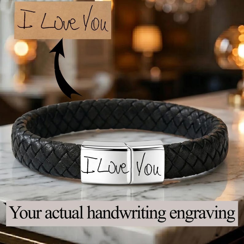 May include: A black braided leather bracelet featuring a rectangular silver-toned metal clasp. The clasp is engraved with the handwritten text I Love You, which matches the sample text shown on a tan rectangular card above the bracelet.