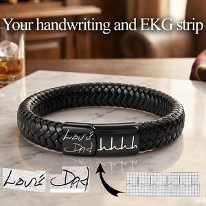 May include: A black braided leather bracelet featuring a rectangular black metal clasp engraved with the handwritten text Love Dad and an EKG heart rhythm line. The image includes text reading Your handwriting and EKG strip above the bracelet.