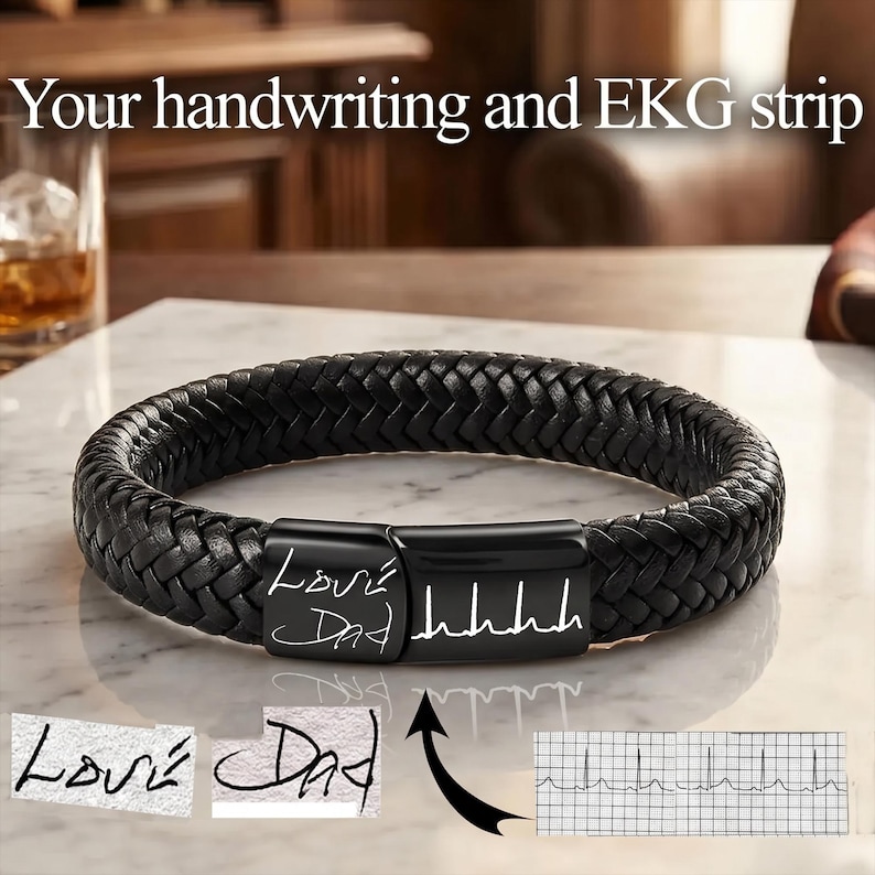 May include: A black braided leather bracelet featuring a rectangular black metal clasp engraved with the handwritten text Love Dad and an EKG heart rhythm line. The image includes text reading Your handwriting and EKG strip above the bracelet.