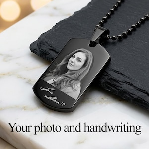 May include: Black dog tag pendant with a black ball chain necklace. The pendant features a black and white photo of a person and handwritten text that reads "Love Sara". The text "Your photo and handwriting" is at the bottom.