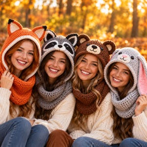 May include: Four crochet animal hoods featuring a fox with orange ears, a raccoon with black and white markings, a brown bear with rounded ears, and a gray rabbit with long pink-lined ears, each integrated into a matching chunky knit cowl.