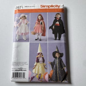 May include: A Simplicity sewing pattern envelope 2571, size A 1/2, 1, 2, 3, 4, featuring illustrations of five children's costumes: a shepherdess, Little Red Riding Hood, a vampire, a fairy with a cone hat, and a star-patterned wizard.