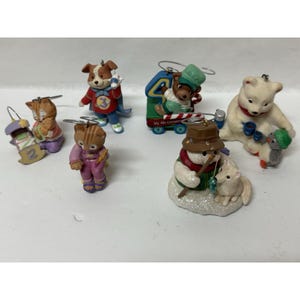 May include: A collection of six holiday ornaments featuring a cat with a number two, a dog with a number three, a bear with a number four, a snowman with a fox, and a polar bear with a penguin. Each ornament includes a metal hanging loop.