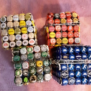May include: Four small square boxes made from bottle caps. The boxes are in different colors: yellow, red, green, and blue. Each box has a wire frame around it.
