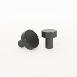 May include: Two black round cabinet knobs with a cylindrical base.