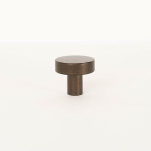 Op de afbeelding: Een ronde, bronzen kastknop met een licht getextureerd oppervlak.
